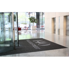 Insitu  product image of a Superguard Logo Inlay Mat installed to a revolving door in an office building entrance.