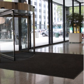 Insitu image of the 3M Nomad Entrance Matting - Aqua Series 85 installed into an indoor area with a revolving door.